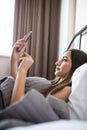 Portrait of beautiful woman waking up in her bed and looks into the phone. Check social networks, send sms Royalty Free Stock Photo