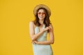 Portrait of beautiful woman wearing trendy summer outfit, straw hat and colorful sunglasses, posing on yellow background Royalty Free Stock Photo