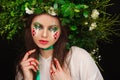 Portrait of a beautiful woman in a white dress with a green ribbon and with branches on her head. Creative makeup Royalty Free Stock Photo