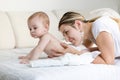 Portrait of beautiful young woman caressing and looking at her baby son lying on bed Royalty Free Stock Photo