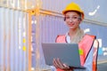 Portrait of beautiful worker woman stand and smile with laptop in cargo container shipping area