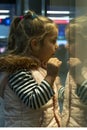 A beautiful 4-year-old blonde girl looks at a glass shop window with admiration. Royalty Free Stock Photo