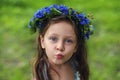 Portrait of beautiful 5 years old girl with blue eyes in wreath from cornflowers knapweeds in summertime with kissing face