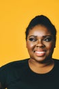 portrait of a beautiful young adult african american woman smiling with afro hairstyle on yellow background Royalty Free Stock Photo