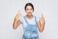 Beautiful woman in overalls showing rock and roll hand sign, looking crazy with devil horn gesture. Royalty Free Stock Photo