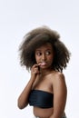 Portrait of beautiful, young, african woman with curly hair, well-kept, smooth, healthy skin posing against white studio