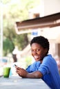 Beautiful young african woman relaxing at outdoor cafe with a smart phone Royalty Free Stock Photo