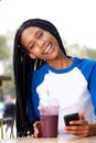 Beautiful young african woman sitting at cafe with mobile phone and drink Royalty Free Stock Photo