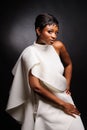 Portrait of a beautiful young African woman in white dress over black background