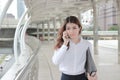 Portrait of beautiful young Asian business woman talking on phone and walking on walkway in city. Royalty Free Stock Photo