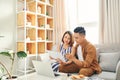 Portrait of beautiful young Asian couple using laptop on the sofa at home Royalty Free Stock Photo