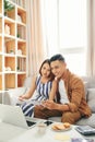 Portrait of beautiful young Asian couple using laptop on the sofa at home Royalty Free Stock Photo