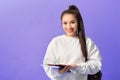 Portrait of beautiful young asian holding notebooks isolated on the violet background