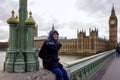 Portrait of beautiful young Asian muslim woman wearing hijab and eyeglasses sitting alone on railing of Westminster Bridge Royalty Free Stock Photo