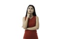 Portrait of beautiful young Asian woman in casual business red dress is looking up, pointing cheek and crossed arm while thinking Royalty Free Stock Photo