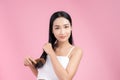 Portrait of beautiful young Asian woman combing her hair, looking at camera and smiling Royalty Free Stock Photo