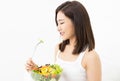 Portrait of a beautiful young Asian woman eating fresh salad from a bowl isolated over white background. Healthy food and people Royalty Free Stock Photo