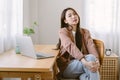 Portrait of beautiful young Asian woman freelancer sitting in comfortable on chair and working on laptop computer in living room Royalty Free Stock Photo