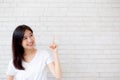 Portrait of beautiful young asian woman happiness standing finger pointing something on gray cement texture grunge wall background Royalty Free Stock Photo