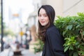 Portrait of a beautiful young Asian woman in long hair wearing a black coat standing smiling happy outdoors in the city Royalty Free Stock Photo