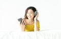 Portrait of beautiful young Asian woman lying down on her bed with eyes closed and listen to music on phone with headphones at Royalty Free Stock Photo