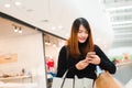 Portrait of beautiful young asian woman in shopping mall, smiling using smart phone to network indoors. Royalty Free Stock Photo