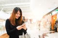 Portrait of beautiful young asian woman in shopping mall, smiling using smart phone to network indoors. Royalty Free Stock Photo