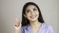 Portrait of beautiful young Asian woman smiling and pointing fingers upward at copy space isolated over white background Royalty Free Stock Photo