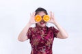 Portrait of Beautiful Young asian woman wear chinese dress traditional cheongsam or qipao. holding orange slices front of her eye Royalty Free Stock Photo