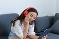 Portrait of beautiful young Asian woman wearing headphones to listening music while relaxing on sofa at home. Relaxing at home Royalty Free Stock Photo