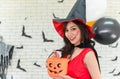 Portrait of beautiful young asian woman wearing witch costume posing with balloons on background decorated for halloween party - Royalty Free Stock Photo