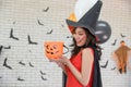 Beautiful young asian woman wearing witch costume posing with balloons on background decorated for party concept Royalty Free Stock Photo