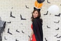 Portrait of beautiful young asian woman wearing witch costume posing with balloons on background decorated for party concept Royalty Free Stock Photo