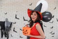 Portrait of beautiful young asian woman wearing witch costume posing with balloons on background decorated for party concept Royalty Free Stock Photo