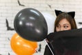 Portrait of beautiful young asian woman wearing witch costume posing with balloons on background decorated for party concept Royalty Free Stock Photo