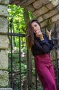 Portrait of a beautiful young and attractive teen girl with long hair near the steel gates of the destroyed stone castle in Royalty Free Stock Photo