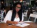 Portrait of beautiful young black woman sitting at cafe and writ Royalty Free Stock Photo