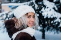 Portrait of beautiful young black woman wearing in fur coat and knitted hat in winter park