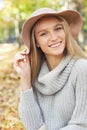Portrait of a beautiful young blond woman with shiny straight hair in a brown hat in the park Royalty Free Stock Photo