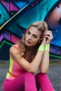 Portrait of beautiful young blonde caucasian woman near wall with graffiti. Outdoors