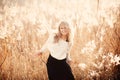 Portrait of a beautiful young blonde girl in a field in white pullover, laughing