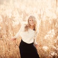 Portrait of a beautiful young blonde girl in a field in white pullover, smiling, concept of beauty and health