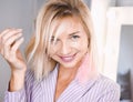 Portrait beautiful young blonde girl posing in the studio with professional make-up and earrings pink feathers in the ears Royalty Free Stock Photo