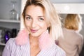 Portrait beautiful young blonde girl posing in the studio with professional make-up and earrings pink feathers in the ears Royalty Free Stock Photo