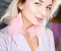 Portrait beautiful young blonde girl posing in the studio with professional make-up and earrings pink feathers in the ears Royalty Free Stock Photo