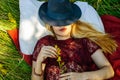 Portrait of a beautiful young blonde girl resting in nature. Girl lying in a field on the grass and smiling. in the hands of the g Royalty Free Stock Photo