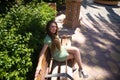 Portrait of beautiful young blonde woman with blue eyes and short dress sitting on park bench. The woman is resting with her legs Royalty Free Stock Photo