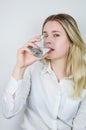 Portrait of a beautiful young blonde woman drinking a glass of water and looking at the camera Royalty Free Stock Photo