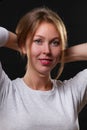 Portrait of a beautiful young blonde woman holding her hair with her hands, on a black background Royalty Free Stock Photo