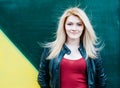 Portrait of a beautiful young blonde woman near green wall. Blowing Long Hair.